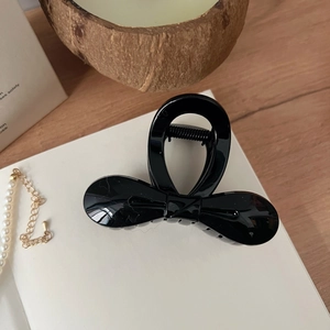 Pince à cheveux noeud papillon noir brillant dans un décor élégant sur une table en bois