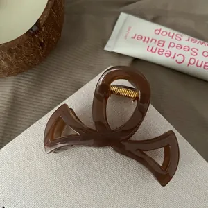 Gros plan d'une pince à cheveux en résine marron avec ressort doré sur présentoir
