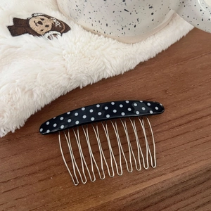 Detailed view of the black polka dot acetate hair comb with ten silver metal teeth