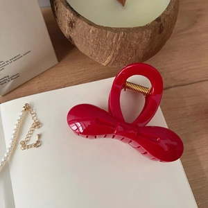Détail d'une pince à cheveux nœud rouge avec ressort doré sur fond élégant