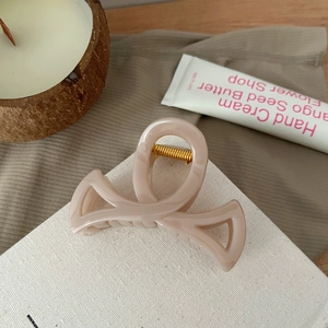 Détail d'une pince à cheveux beige mat évidée munie d'un ressort en métal doré robuste