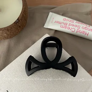 Gros plan sur une pince à cheveux mate noire de 8,5 cm sur un fond crème minimaliste
