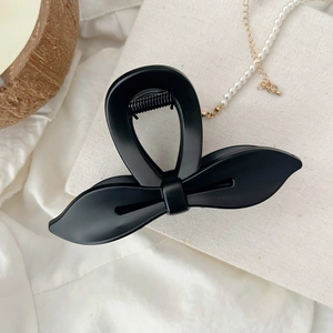 Gros plan d'une pince à cheveux papillon noir mat sur un fond esthétique élégant