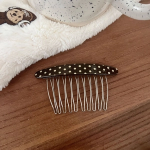 Close-up of a sweet polka dot acetate hair comb with metal teeth on a wooden table