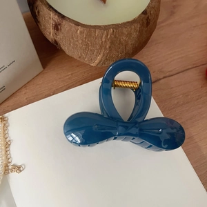 Détail de la pince à cheveux noeud bleu marine avec ressort doré et finition brillante élégante