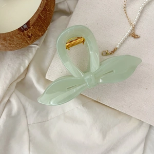 Détail de la pince à cheveux feuille vert clair avec ressort doré sur tissu en coton