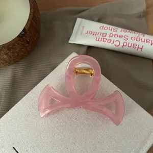 Détail d'une pince à cheveux rose translucide évidée avec ressort en métal doré