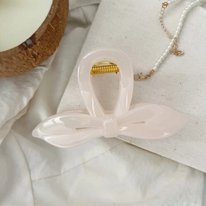 Détail d'une élégante pince à cheveux papillon rose clair avec ressort doré sur tissu