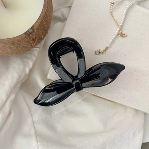 Détail d'une grande pince à cheveux nœud noir élégante avec perles et décor moderne