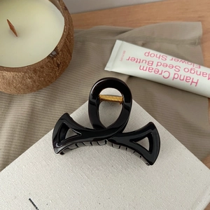 Détail d'une pince à cheveux de 8,5 cm avec ressort doré et finition noire lisse élégante