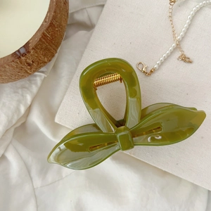 Détail de la pince à cheveux vert matcha avec ressort doré et design irrégulier élégant