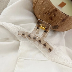 Close-up of leopard print hair claw clip with gold spring on white lace fabric