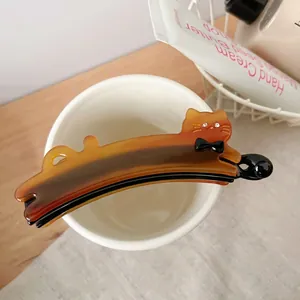 Vue détaillée de la pince banane chat avec strass posée sur une tasse blanche