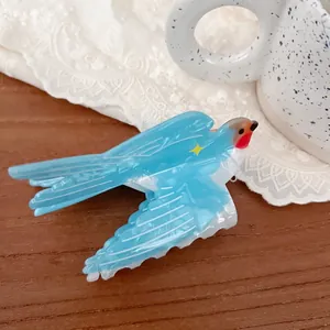 Exquisite blue bird hair claw clip with star detail on a warm wooden surface