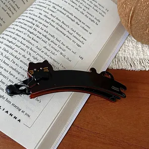 Détail d'une pince banane chat faite main avec nœud doré et lettrage FRANCE sur un livre