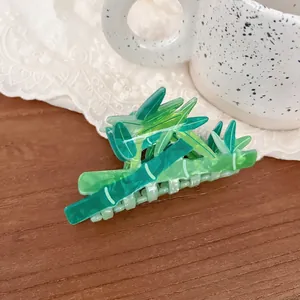 Bamboo style green hair claw clip with leaf design on a wooden desk background