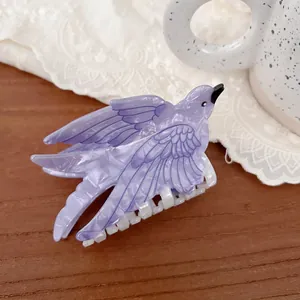 Macro detail of bird-shaped lilac acetate hair claw clip with marble texture on lace