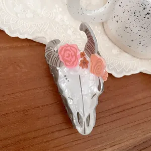 Detailed view of longhorn skull hair claw with floral accents on a rustic wooden desk