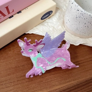 Detail of pink marble textured acetate reindeer hair claw clip on a vintage wooden table