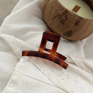 Detail view of tortoiseshell resin hair claw clip with square geometric design on lace