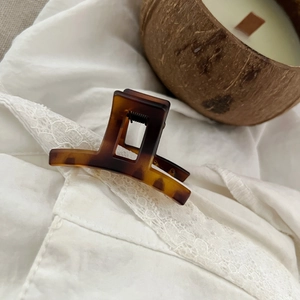 Macro shot of 5cm tortoise shell hair claw clip on white lace with candle background
