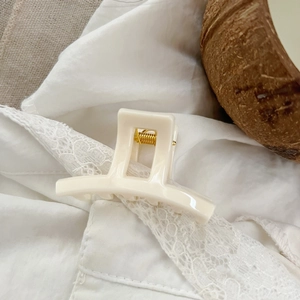 Close-up of cream hair claw clip with golden metal spring on elegant lace fabric