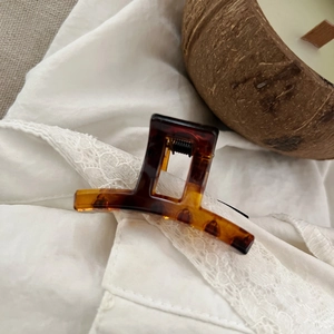 Detailed macro view of a tortoiseshell resin hair claw clip on white textured fabric