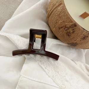 Glossy chocolate brown small square hair claw clip with gold spring detail on lace fabric