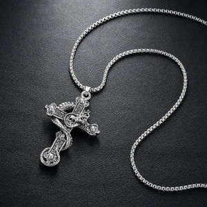 Gothic silver snake and skull cross necklace pendant on black textured background
