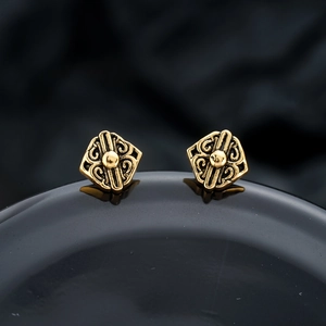 Macro detail of vintage gold screw-back studs with filigree auspicious cloud engraving
