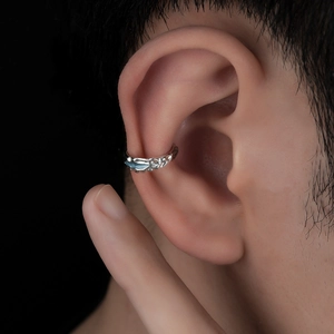 Detailed close-up of irregular textured silver ear cuff on model with black background