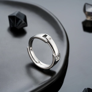 Close-up of adjustable silver ring with a small zircon on a black ceramic plate