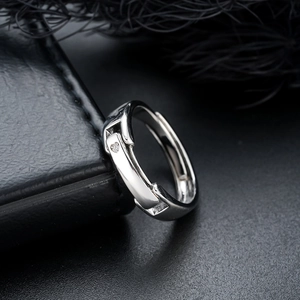 Close-up of adjustable silver ring with small sparkling stones on black leather background