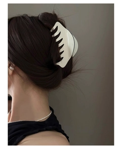 Détail d'une pince à cheveux crème élégante avec bords ondulés sur cheveux bruns