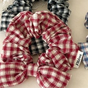Detailed close-up of plaid bow hair scrunchies in red black and blue woven fabric