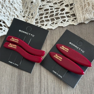 Detail of wine red acetate hair clips in wave and oval shapes on a display card