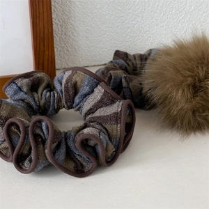 Dettaglio di elastico in maglia a righe e pompon di peluche per acconciature invernali