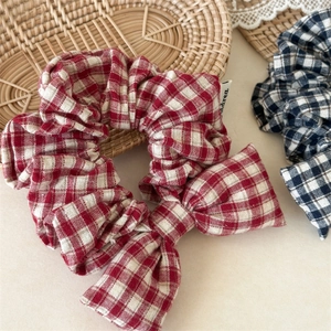 Macro detail of red and blue checkered bow scrunchies on a rustic rattan background