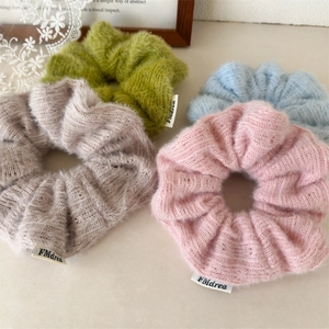 Gros plan de chouchous en maille duveteuse en quatre couleurs pastel avec étiquette FMdrea