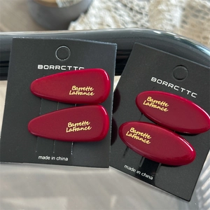 Detail view of deep red acrylic hair clips with gold lettering on display cards