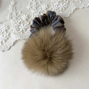 Dettaglio di elastico per capelli a righe con un grande pompon di pelliccia marrone soffice