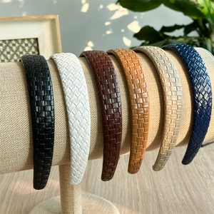 Detail of six plaid textured leather headbands in vintage colors on a linen stand
