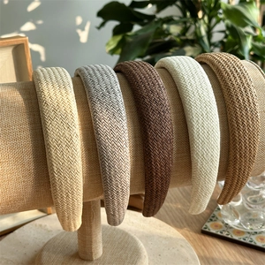 Détail de cinq bandeaux en paille tissée exposés sur un support en lin naturel sobre