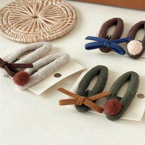 Détail des barrettes d'hiver en feutre avec nœuds et boules en peluche sur carte
