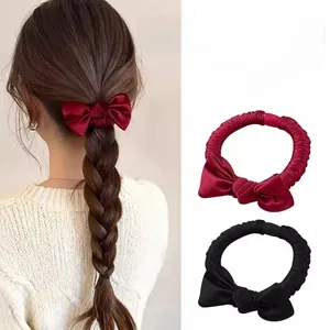 Close-up of silk satin hair scrunchies with large bows in burgundy and black colors