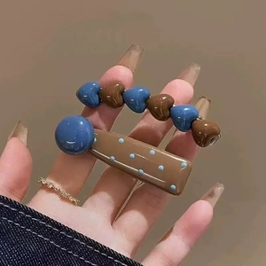 Close-up of stylish resin heart and polka dot hair clips held in hand for hair styling