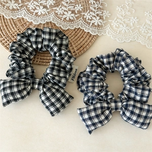 Close-up of black and white gingham bow scrunchies with soft cotton fabric texture
