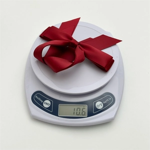 Detail shot of a dark red satin bow hair tie on a digital scale weighing 10.6g