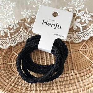 Close-up of black high-elastic hair bands with textured finish on a lace background