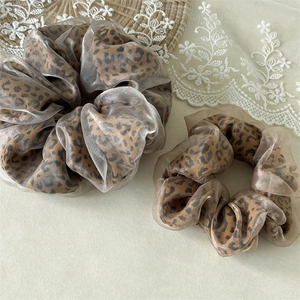 Détail des chouchous imprimé léopard en maille avec superposition d'organza champagne